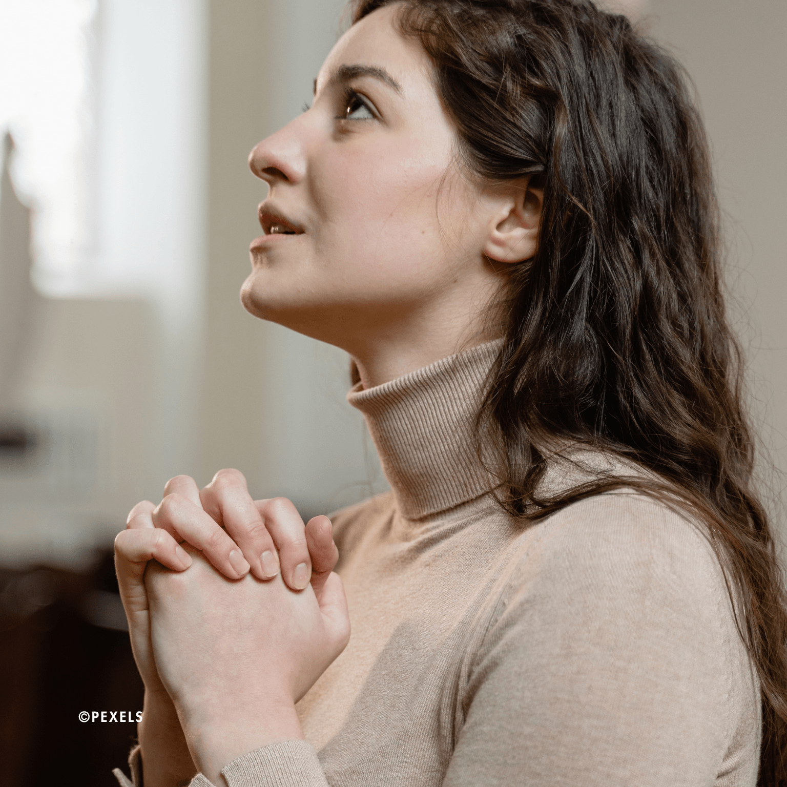 une femme prie, les mains jointes